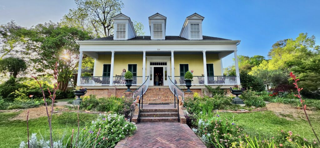 Historic white house with porch and colorful garden